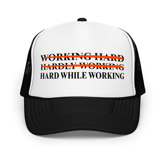 Inappropriate funny mesh trucker hat with bold black text that says “Working Hard Hardly Working Hard While Working” — a hilarious hat for men who love innuendos, dirty humor, and wearing something outrageous to work or parties.